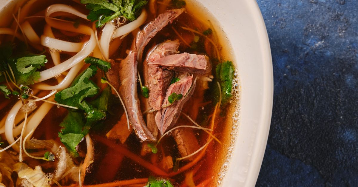Vietnamesische Pho-Suppe mit frischen Kräutern und japanisches Sushi nebeneinander angerichtet